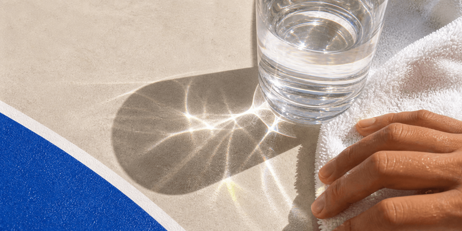 Glass, towel, and cobalt track refractions in hard sunlight.