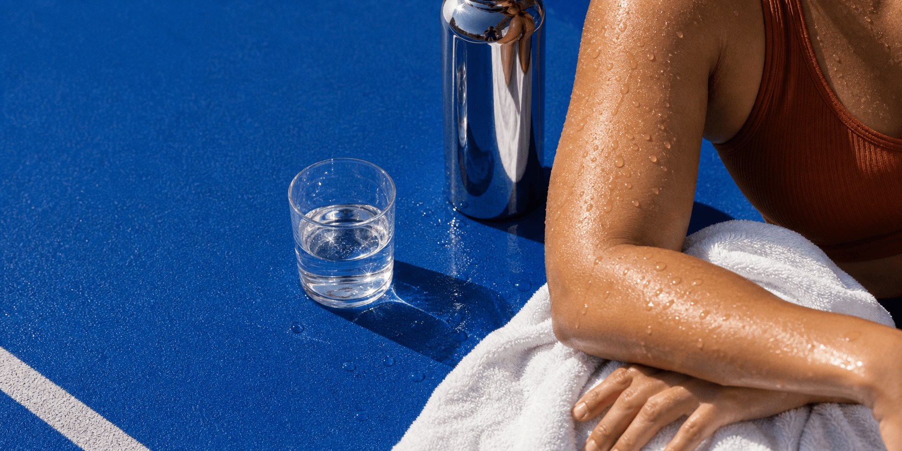 Adult resting on a track beside a water bottle and towel.